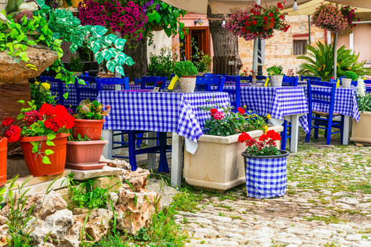 Traditional Greek Taverna with Red Geranium Flowers, Close-up Rustic Tables in Omodos Village, Mediterranean Aesthetics. authentic Cypriot Lifestyle, Greece Style Restaurant Decor, High Res photo
