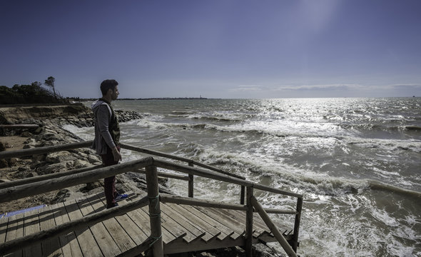 Hombre joven de pie en el muelle mirando al mar
