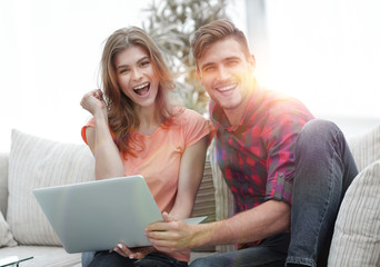 young couple rejoices,sitting on the couch in front of the open laptop