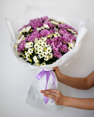 Beautiful woman hold bouquet of chrysanthemum flowers yellow and purple on white