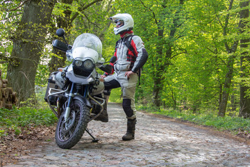 Reiseenduro Motorrad im Wald mit Fahrer - Blick in die Ferne - obrazy, fototapety, plakaty