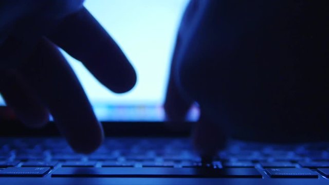 Hands typing text on the laptop keyboard. Night theme