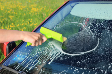 Auto serwis, kierowca myje przednią szybę w samochodzie osobowym,