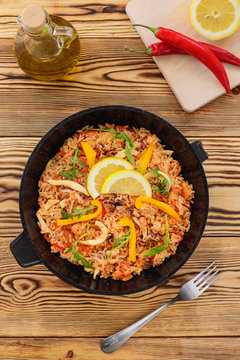 Spanish paella in a frying pan on a wooden background