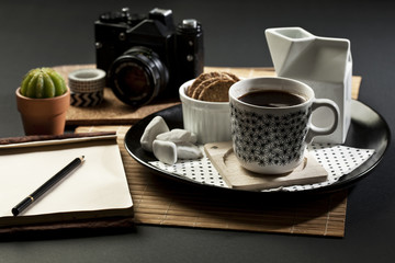BlaTable set with coffee,  camera and note pad with empty space fot writing