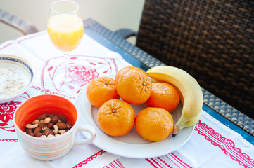 Breakfast on the table, juice, cereal and fruits in the sun. Good food, proper breakfast, strawberries, tangerines, bananas, nuts