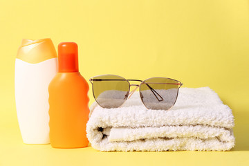 sunscreen, towel, hat on a colored background. Cosmetics for safe sunburn.