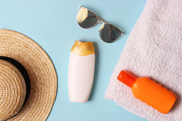 sunscreen, towel, hat, glasses on a colored background. Cosmetics for safe sunburn. top view,...