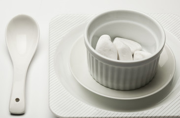 Fototapeta na wymiar White ceramic dishware with marshmallows on white background