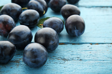 Ripe and sweet plums on blue wooden table