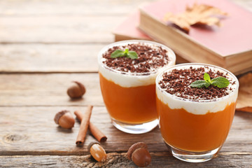 Pumpkin smoothie in glasses with cinnamon and acorns on wooden table
