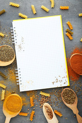 Blank white notebook with different spices on wooden table