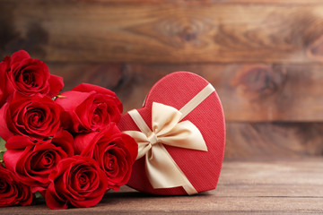 Bouquet of red roses with gift box on brown wooden table