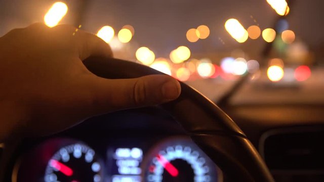 Man Hands Driving Car In The Night Road Traffic. POV