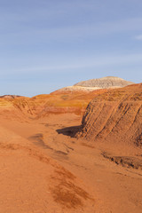 Fototapeta na wymiar Multicolored red, orange and yellow striped hills under a bright blue sky in Eastern Kazakhstan