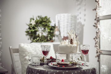 Table for two with white cake, chocolate biscuits and red wine