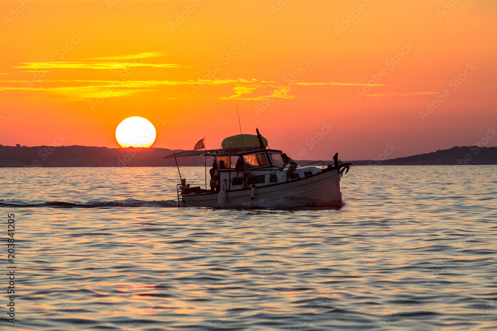 Wall mural sunset over sea with silhouette of small boat