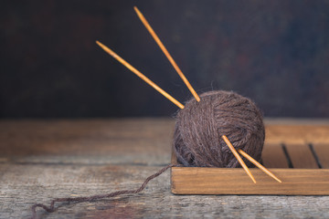 Wool yarn with wooden needles on a rustic background, autumn wabi sabi concept