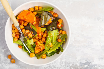 Salad with baked pumpkin and chickpeas with mustard-honey dressing in a white plate, top view. Healthy vegan food concept.