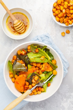 Salad with baked pumpkin and chickpeas with mustard-honey dressing in a white plate, top view. Healthy vegan food concept.