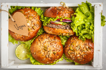 Vegan bean burger with vegetables and tomato sauce in a white wooden box, top view. Healthy vegan food concept.