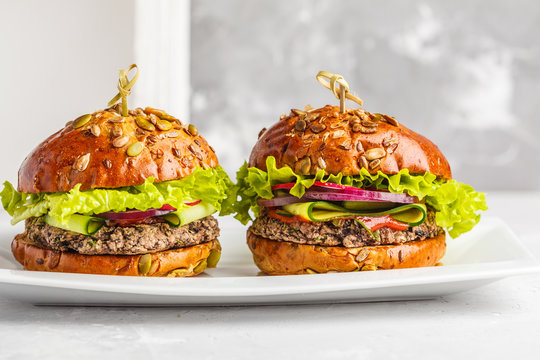 Vegan bean burgers with vegetables and tomato sauce on white dish, copy space. Healthy vegan food concept.