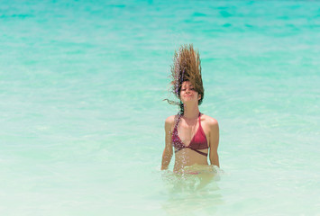Obraz premium Happy woman in red bikini is playing and splashing in the sea