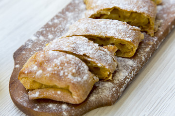 Strudel or apple pie on wooden board. Closeup.