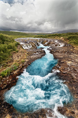 Scenic view of a waterfall with blue coloring, in the background a mountain range - Location: Iceland, Golden circle