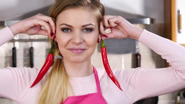 Cheerful woman having fun pretending chilli red hot pepper is her earrings. Healthy vegetable, dieting food concept.