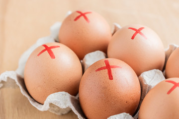 Brown farm eggs with red cross in white carton. Eggs recall over salmonella. How to buy safest eggs after recall