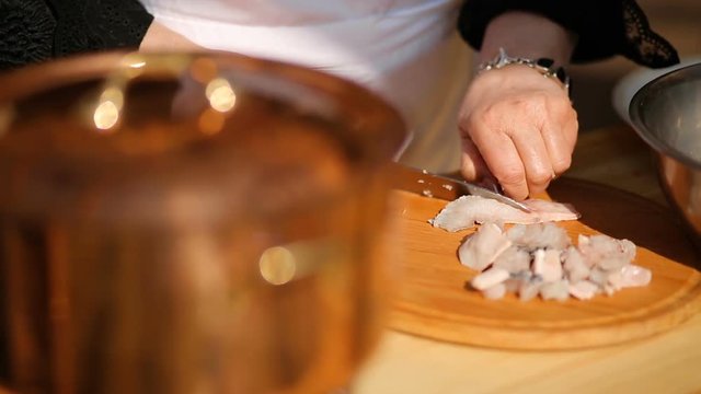 slicing fish on a wooden cutting board with a knife