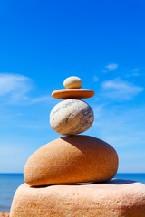 Stones balance on a background of blue sky and sea