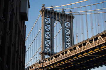 Close-up view of the Brooklyn bridge seen from a narrow alley during the sunset. New York City, USA.