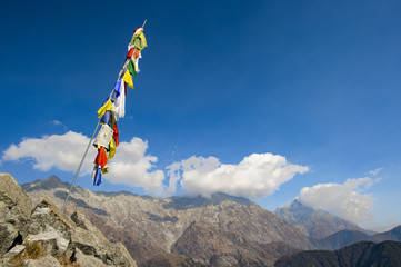 Colorful Tibetan flags with mantras on the summit of a Himalayan mountain with a blue sky and some clouds