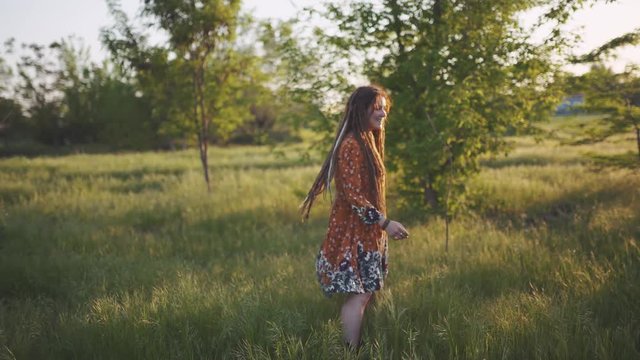 attractive fun hippie woman with dreadlocks in the woods at sunset having good time outdoors