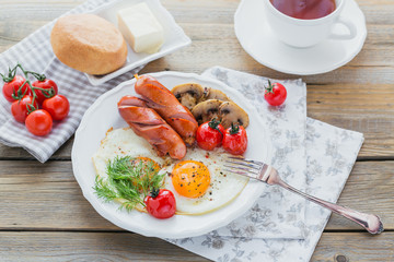 English breakfast with fried eggs, sausages, mushrooms, grilled tomatoes