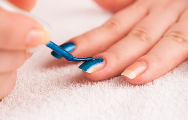 Obraz na płótnie Canvas Woman applying dark blue shiny nail polish on middle finger