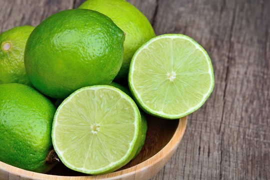 Fresh lime in a bamboo bowl on wood table