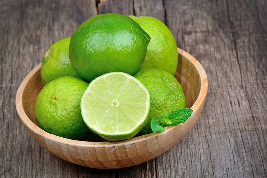 Group of fresh lime in a bamboo bowl on rustic table