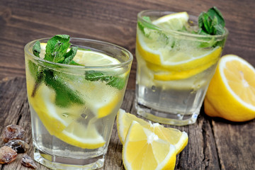 Water with fresh lemon and mint on wood background