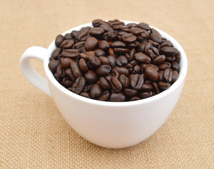 Cup and coffee beans on burlap background