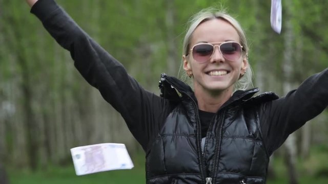 A girl with a wad of cash, throws the bills up enjoying wealth.