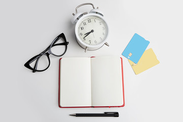 Mockup of two blank credit cards, headphones, eye glasses and retro alarm clock on empty white desk. Business empty mock-up background for message writing.Top view concept