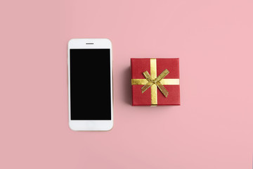 Mockup of smartphone, gift box on empty pink clean desk. Business mock-up background for message writing.Top view. Horizontal