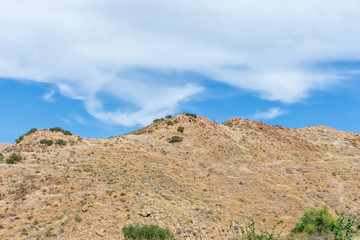 Fototapeta na wymiar Blue sky and white clouds over extremely dry hillside in desert