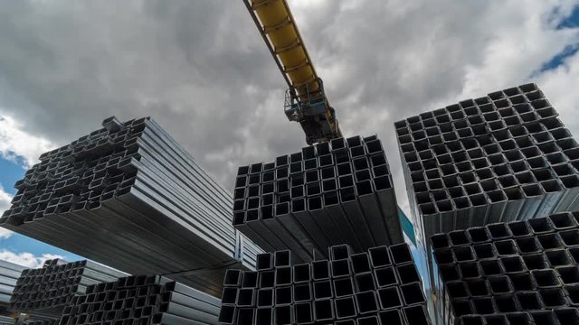 Metallic, steel or aluminum rectangular pipes and tubes on warehouse. Time lapse. Moving clouds