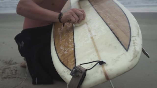 Surfer Waxing Board In The Shorebreak In Slow Motion