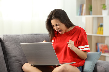 Excited teenager receiving good news online at home
