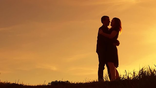 silhouette man circling girl amusement hugs at sunset. Man and woman silhouette in sunset slow motion. Couple in love kissing at sunrise. man and girl embrace silhouette lifestyle family concept